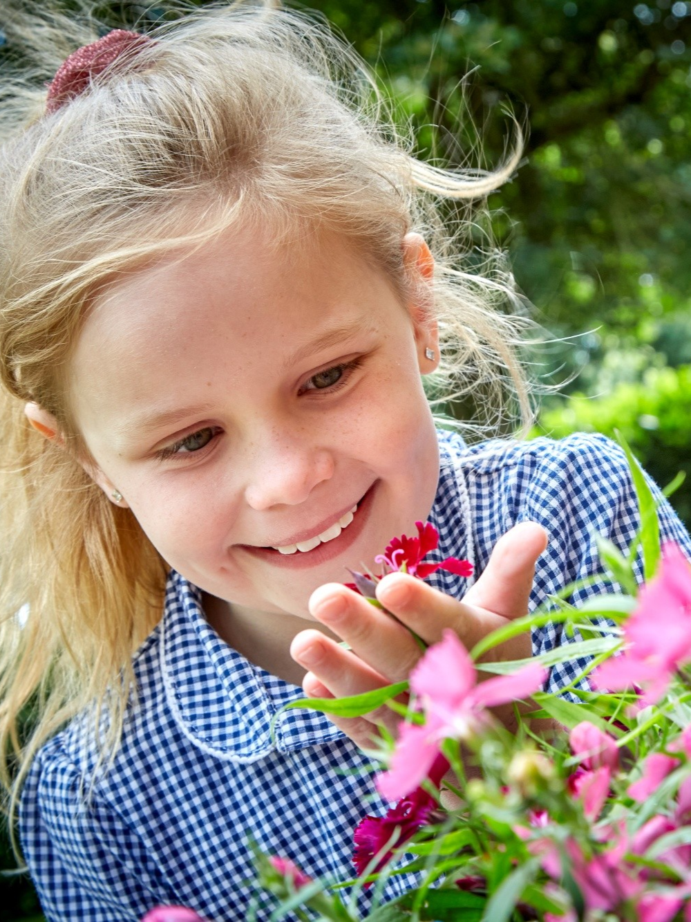 Croxby student smiling at a flower